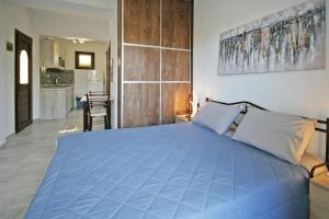 a bedroom with a blue bed and a kitchen at Villa Angela in Vourvourou