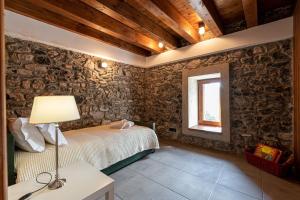 a bedroom with stone walls and a bed with a lamp at Anastasia House in Nimfasía