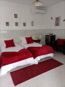 a bedroom with two beds with red and white sheets at Casa Zanzibar Hotel in Landeira