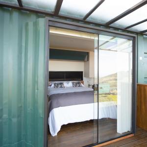 sypialnia z łóżkiem i szklaną ścianą w obiekcie Refúgio Eco Boutique Tuiuva w mieście Cristina