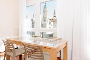 une table à manger avec des chaises et une fenêtre dans l'établissement Apartamentos Sabinas El Pilar, à Saragosse
