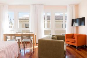 a living room with a couch and a table and chairs at Apartamentos Sabinas El Pilar in Zaragoza