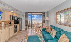 a living room with a blue couch and a kitchen at 4th Floor Oceanfront 1 Bedroom Suite! Beach Cove Resort 411 in Myrtle Beach