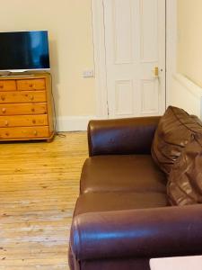 a living room with a leather couch and a television at Apex Haymarket Apartment in Edinburgh
