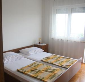 Schlafzimmer mit einem Bett mit weißer Bettwäsche und einem Fenster in der Unterkunft Apartments Ivan in Crikvenica