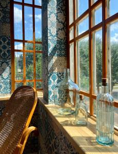 a table with glass bottles and a chair and windows at Olive Apartment in Liepāja