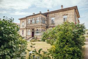 an old house with trees in front of it at Olive Apartment in Liepāja
