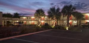 a parking lot in front of a building with palm trees at Melbourne All Suites Inn near I95 in Melbourne