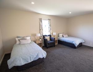 a bedroom with two beds and a chair and a window at Tuscany Downs Estate in Darfield