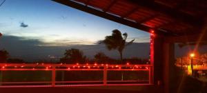 uma vista para um alpendre com luzes vermelhas numa cerca em Casa Friozinho da serra em Guaramiranga