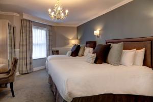 a bedroom with a large bed and a chandelier at Best Western Plus Kenwick Park Hotel in Louth