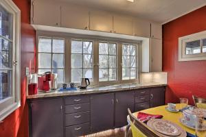 a kitchen with red walls and a table with a tableablish at Homey Cottage with Sunroom and Smart TV! 