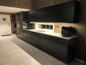 a kitchen with black cabinets and a sink at Hytte nær vannet, jacuzzi og sauna in Vradal