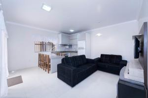 sala de estar con sofá negro y cocina en Casa à 80m da praia, en Bombinhas