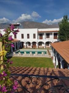 a large white building with a balcony overlooking a river at Iraola Hotel Boutique in Cafayate