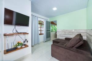 a living room with a couch and a flat screen tv at Recanto da Conceição in Bombinhas