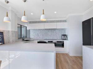 a kitchen with white cabinets and a white counter top at Dolphin Court Penthouse in The Entrance