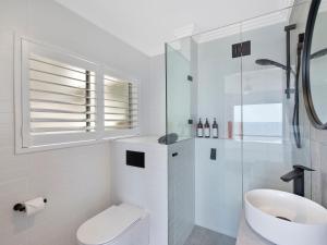 a white bathroom with a toilet and a sink at Dolphin Court Penthouse in The Entrance