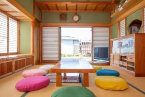 古民家再生ホテル　Relink في فوجيوشيدا: غرفة معيشة مع طاولة وكراسي ملونة