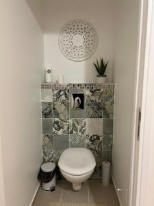 a bathroom with a toilet and a tile wall at PARENTHESE LOVE - Bali Mon Amour Suite Balneo SPA Proche Orly-Paris in La Ville-du-Bois