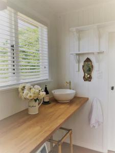 La salle de bains est pourvue d'un lavabo et d'un vase de fleurs sur un comptoir. dans l'établissement Strasbourge Cottage, à Martinborough