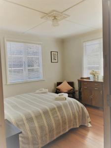 une chambre avec un lit et un ventilateur de plafond dans l'établissement Strasbourge Cottage, à Martinborough