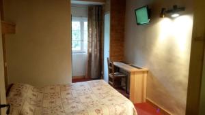 a bedroom with a bed and a desk and a television at Hôtel Les Bernards in Praz-sur-Arly