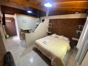 1 dormitorio con cama y pared de ladrillo en Departamentos Centro El Calafate en El Calafate