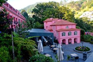 エストレイト・デ・カッマラ・デ・ロボスにあるBIO Hotel - Hotel Quinta da Serraのピンクの建物の景色を望む客室で、テーブルと傘が備わります。