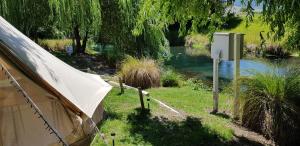 a tent sitting in the grass next to a river at Spring Creek Holiday Park in Blenheim