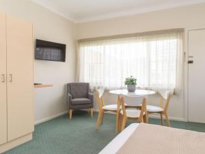 een kamer met een tafel en stoelen en een raam bij Pacific Motel 09 in Forster