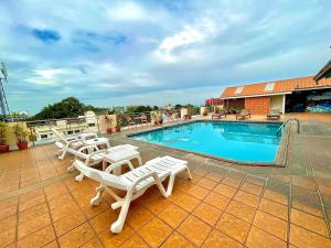 a swimming pool with white lounge chairs next to it at Green Beach Pattaya in North Pattaya