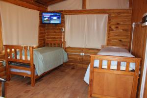 a bedroom with two beds and a television in a cabin at Amaneceres de San Isidro in José de la Quintana