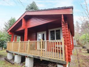 a red tiny house with a large porch at Rowan Lodge in Strathpeffer
