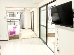 a living room with a flat screen tv on a wall at Court Saiwaicho in Osaka
