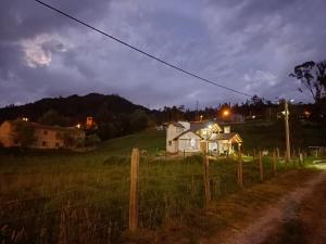 a house on a hill in a field at night at Cabaña El Encanto De ALU in Paipa