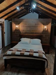 Bett in einem Zimmer mit Ziegelwand in der Unterkunft Cabaña El Encanto De ALU in Paipa