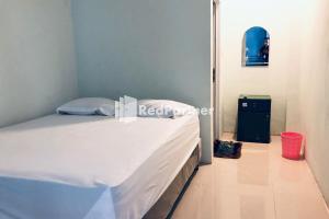 a bedroom with a bed with white sheets and a window at Wisma Suci Syariah Polewali Mandar Mitra RedDoorz in Matakali