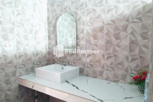 a bathroom with a white sink and a mirror at Wisma Suci Syariah Polewali Mandar Mitra RedDoorz in Matakali +12 photos