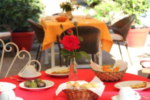 einen roten Tisch mit Teller mit Essen und eine Vase mit einer Rose in der Unterkunft Gli Arancini in Quarrata