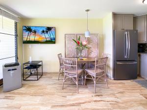 uma cozinha com uma mesa e cadeiras e um frigorífico em Waiohuli Beach Hale D227 - Aloha La'i - Oceanfront/1b1b/Wifi/AC/Cable/Pool/Extras em Kihei