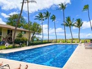 a swimming pool with palm trees and a house at Waiohuli Beach Hale D227 - Aloha La'i - Oceanfront/1b1b/Wifi/AC/Cable/Pool/Extras in Kihei
