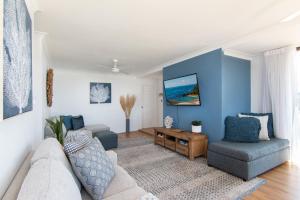 uma sala de estar com paredes azuis e um sofá e cadeiras em Time and Tide 1 em Tuncurry