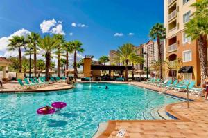 a large swimming pool with blue chairs and palm trees at Premier Resort Condos Near Disney & Universal in Orlando