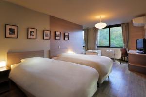 una camera d'albergo con due letti e una televisione di Hotel Ryu Resort and Spa a Takayama