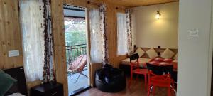 a room with a balcony with a table and chairs at The River View Homestay in Kurseong