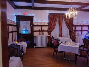 a restaurant with white tables and chairs and a chandelier at Marmora and Lake Inn and Victorian Diner in Marmora