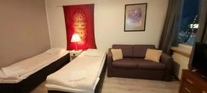 イヴァロにあるIvalo Apartmentのベッド2台とソファが備わる小さな客室です。