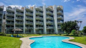 a large apartment building with a swimming pool at The Umdloti Lighthouse Tripelx in Umdloti