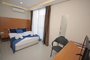 a bedroom with a bed and a desk and a computer at Saatlı Hotel in Çeşme